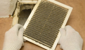 Man removes dust ventilation grilles in white gloves