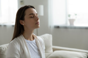 calm woman breathing in fresh air from air quality in the home humidifier dehumidifier in home