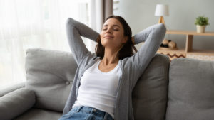 woman sitting on couch breathing fresh air in her home thanks to wave air purifier